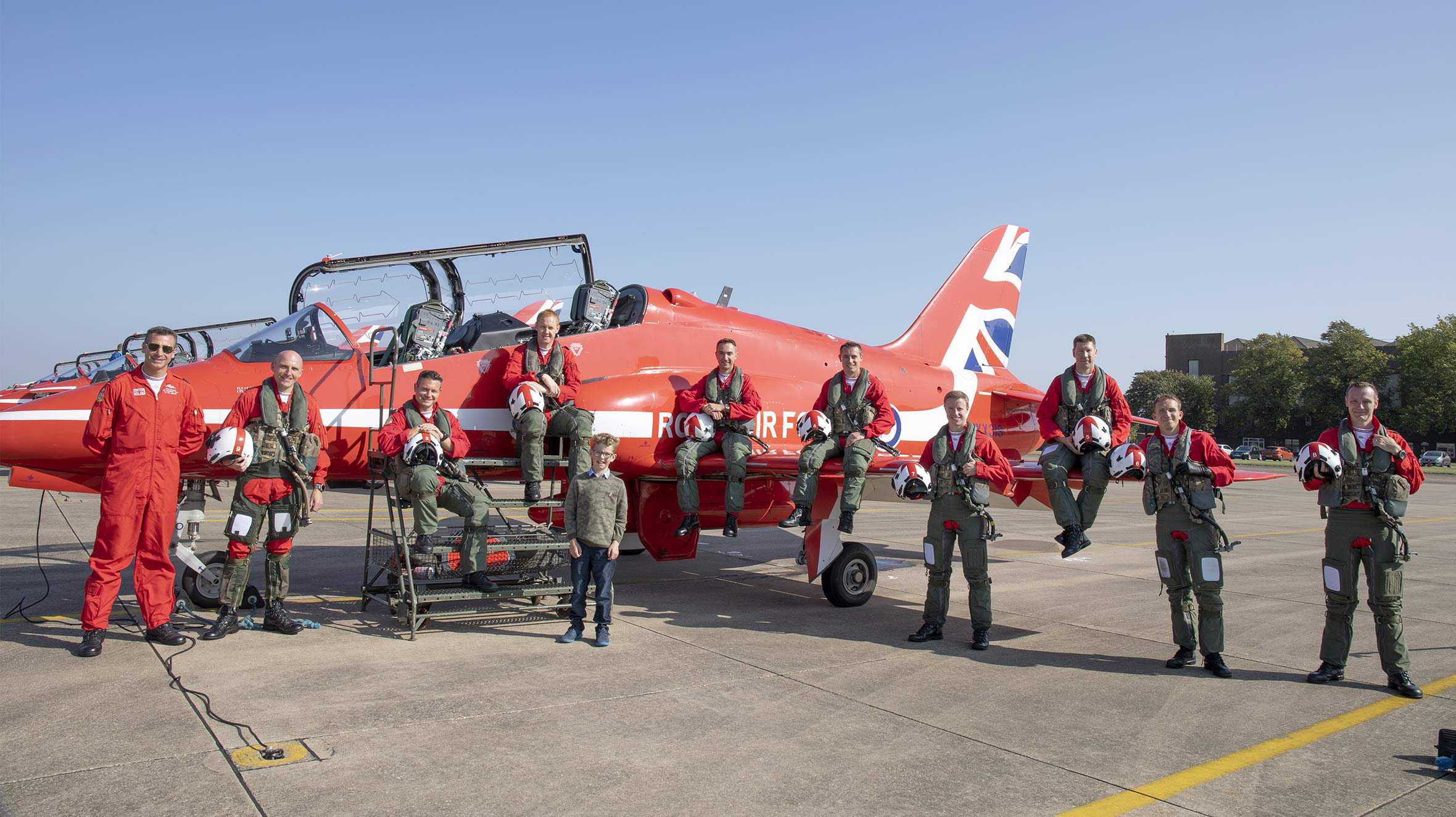 John posing in front of a Red Arrows jet with the pilots and ground crew.