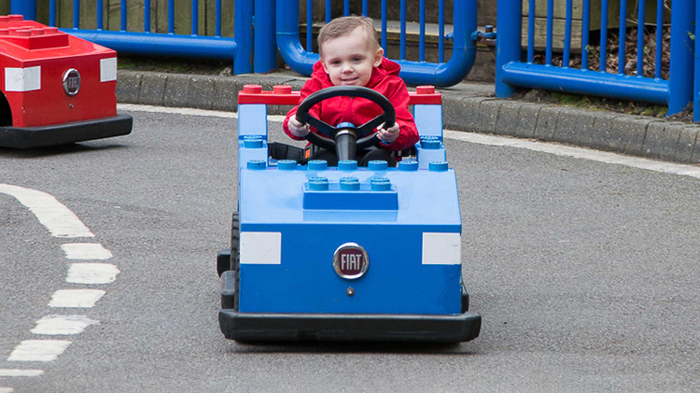 Zak driving a blue Lego go-kart, during his trip to Legoland.